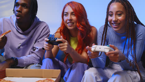 Group-Of-Gen-Z-Friends-Sitting-On-Sofa-At-Home-Gaming-And-Eating-Takeaway-Pizza-2